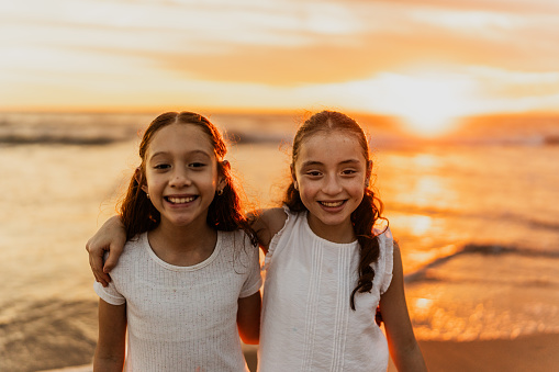 Portrait of child female friends embracing on the beach