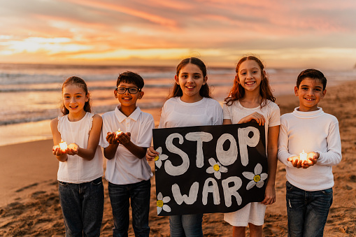 Portrait of child friends protesting against the war on the beach