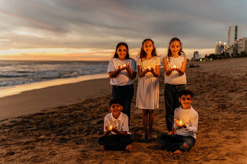 Portrait of child friends holding a candle on the beach