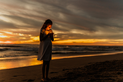 Child girl holding a candle on the beach