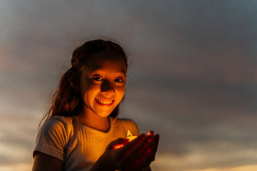 Portrait of a child girl holding a candle outdoors