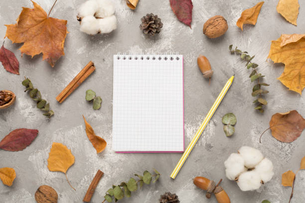 istock Autumn leaves with notebook on concrete background, top view 1818218328