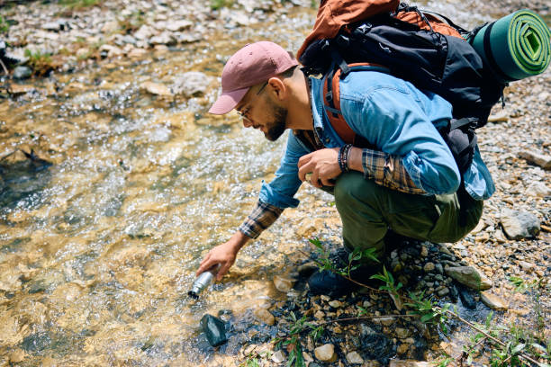 istock Young backpacker refiling his drinking bottle with fresh mountain creek water while hiking in nature. 1818221108