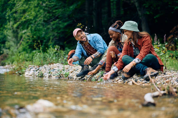 istock Happy hikers having fun while splashing water by mountain creek. 1818221154