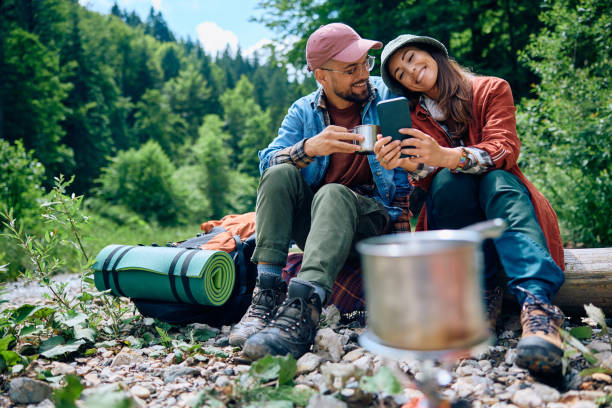 istock Happy couple using smart phone while camping in nature. 1818221228
