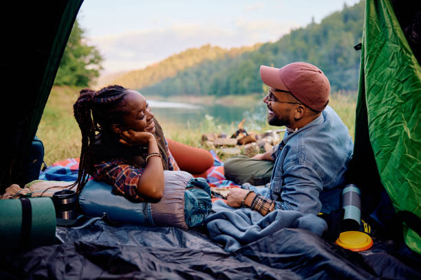 istock Happy multiracial couple talking while relaxing in tent on camping in nature 1818221582