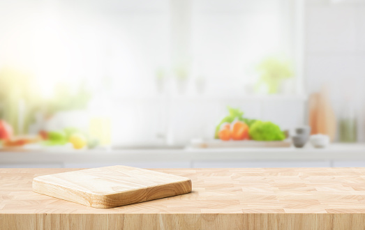 Selective focus.End grain wood counter top with cutting board on blur kitchen in morning window background.For montage product display or design key visual