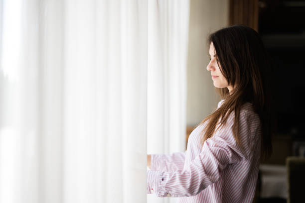 istock Young beautiful brunette woman at the window light background. 1818242828