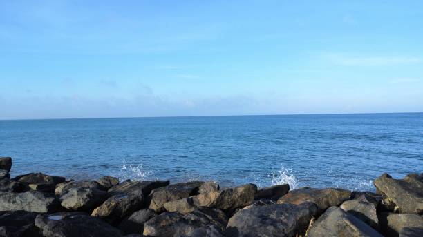 Tranquil beach scene with large stones on the shoreline with waves rolling in