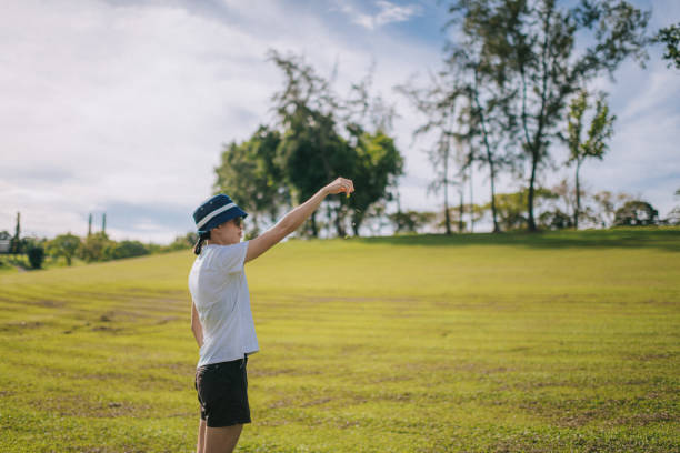 азиатская китаянка-гольфистка проверяет направление ветра перед ударом - golf golfer examining wind стоковые фото и изображения