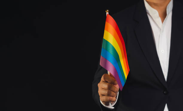 istock Rainbow flag showing in hand while standing against a black background 1818276920