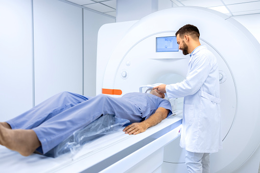 Experienced radiologist holding head coil in MRI examination room preparing for brain scan.