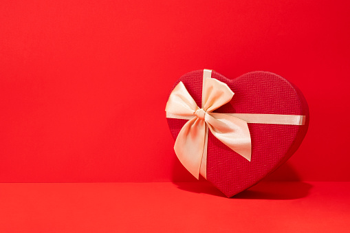 Red heart shaped gift box on red background with copy space for holidays and special days