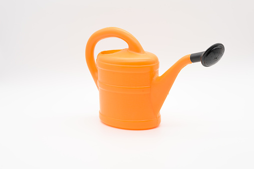 Orange watering can from the side with black watering spray, isolated against a white background