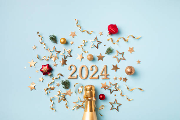 2024 golden champagne bottle Christmas and New Year composition with fir tree, party streamers, confetti stars and holiday decorations. stock photo
