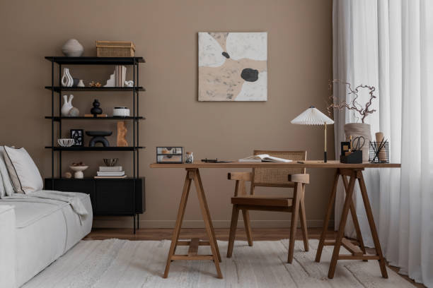 istock Creative composition of warm and cozy workspace interior with mock up poster frame, wooden desk, modular sofa, black rack, rattan chair, stylish lamp and personal accessories. Home decor. Template. 1818326286