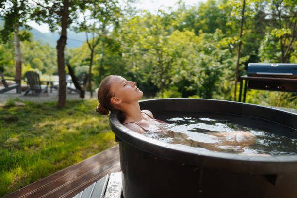 Young woman taking an ice bath Photo of a young woman having a spa day in the cabin in the woods; she is taking an ice bath after using the sauna just do it stock pictures, royalty-free photos & images