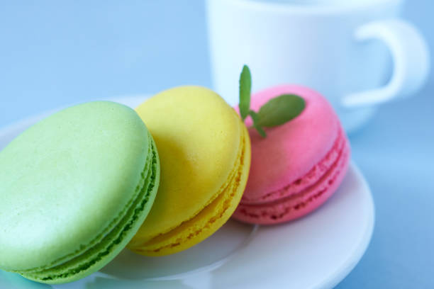 Colorful macaroons on a white plate and a cup of coffee