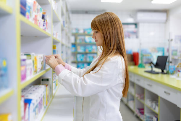 istock Redhead female pharmacist arranging medicine on a shelf. 1818344698