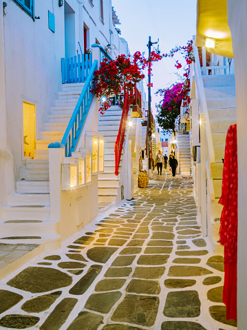 Mykonos Greece in the evening, colorful streets of the old town of Mykonos, Traditional narrow street with blue doors and white walls and street lanterns, shopping street, Mykonos town Greece