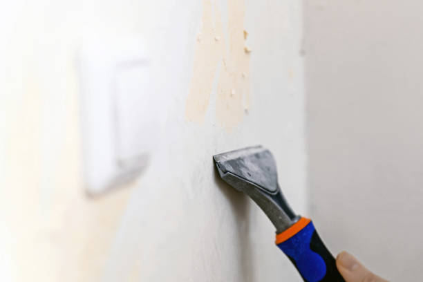 istock Cleaning the wall from old wallpaper with a special scraper 1818348057
