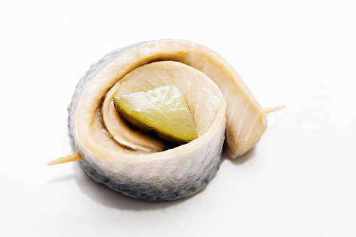 A rollmop, pickled herring fillets rolled around a sliced pickled gherkin. Rollmops are a traditional dish that can be traced back to Northern Europe and have been a staple food. They gained popularity in Germany in the early 19th century and are now commonly eaten in large parts of the world, and are also associated with Ashkenazi Jewish cuisine.