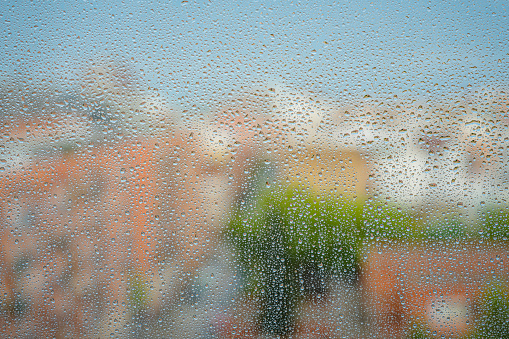 Raindrops on a glass with defocused cityscape at background