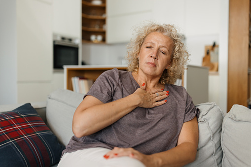 Mid adult woman having chest pain in the sofa