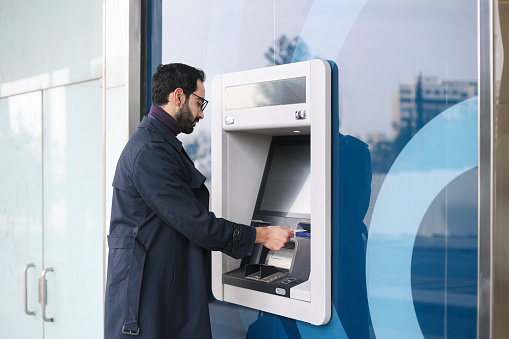 Mid adult Arab man using an ATM. About 35 years old, Middle eastern male.