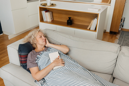 Mid adult woman lying in the living room sofa with terrible headache