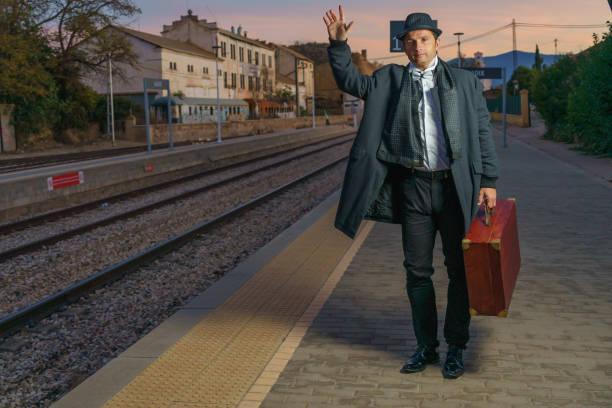 Man on the station platform with suitcase waving goodbye, it is dawn and he is going to work in a very elegant way.