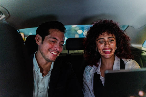 istock Happy coworkers talking using digital tablet inside a taxi 1818387057