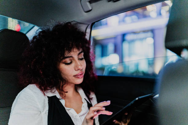 istock Young businesswoman using a digital tablet inside a cab 1818387076
