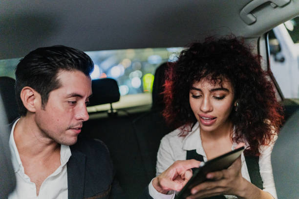 istock Coworkers using digital tablet inside a taxi 1818387382