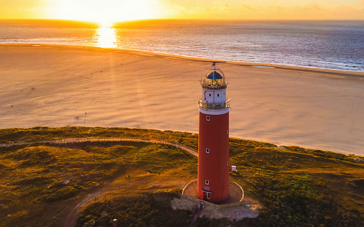 Texell lighthouse during sunset Netherlands Dutch Island Texel in summer with sand dunes at the Wadden Island. drone aerial view from above during sunset at the beach with a sunset in the ocean