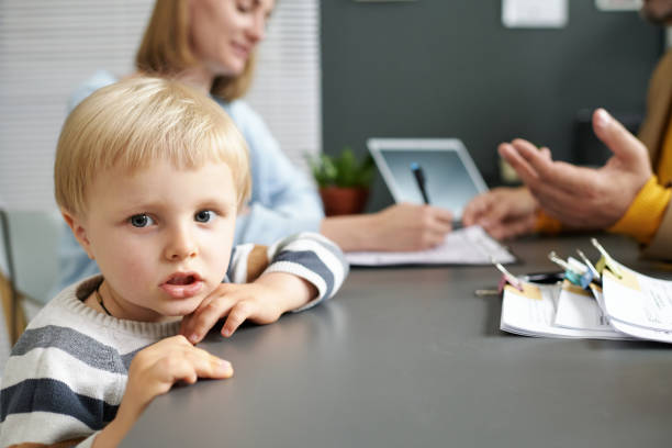 istock Little boy sitting in office with his mom 1818414589
