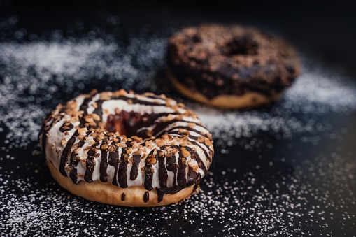 two delicious donuts are sprinkled with powdered sugar from a sieve