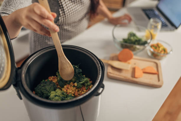 Hispanic woman using slow cooker while preparing food in the kitchen