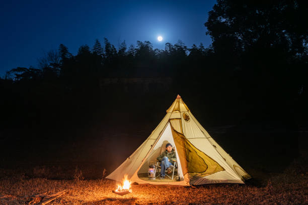 istock Camping under the moonlight, a man sitting in the tent, campfire 1818463417