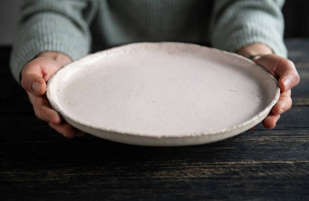 istock Woman hands holding blank plate on wooden table 1818463421