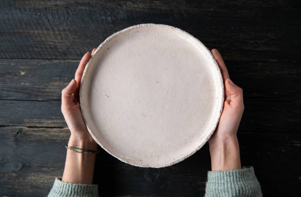 Woman hands holding blank plate on wooden table