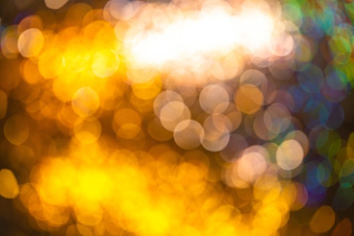 A calm blurred yellow-brown background with colored bubble-shaped spots with a light coming from the upper corner of the image