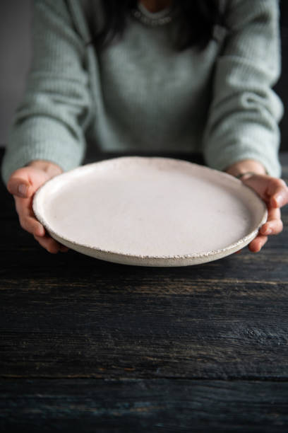 istock Woman hands holding blank plate on wooden table 1818465121