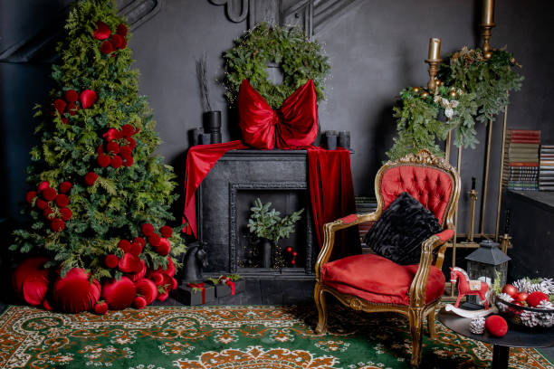 istock Hall room with a black fireplace with red bow on it and balls under designer tree with lights near the queen chair. Christmas Сelebration atmosphere. Black and red interior 1818470519