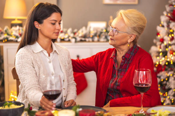 Mother and daughter talking while having Christmas dinner at home stock photo