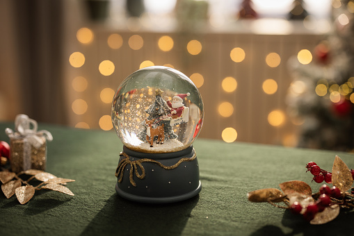 Snow globe on the table against Christmas tree.