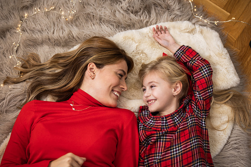 Mom and daughter in a decorated Christmas living room laying on the floor and laughing