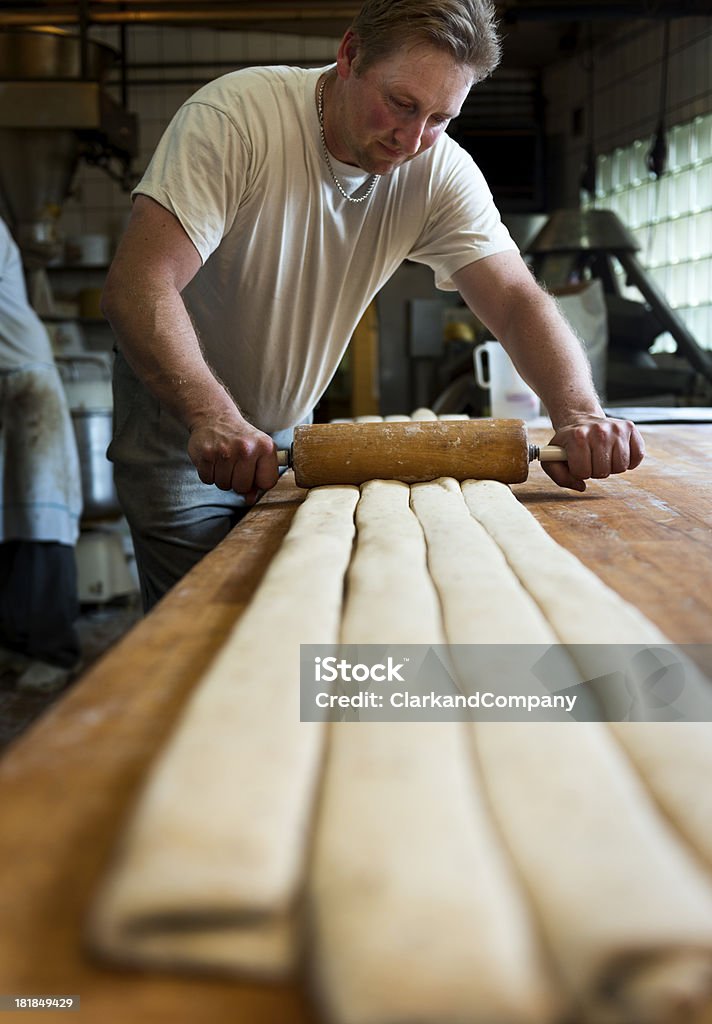 Baker rotolare la pasta nella sua panetteria - Foto stock royalty-free di Panettiere