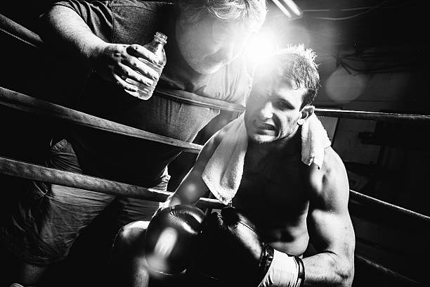 Boxer Coach encourages Boxer sitting in boxing ring corner. lightweight weight class stock pictures, royalty-free photos & images