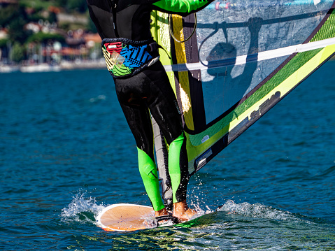 Photo of a windsurfer in mid-air during a jump over a wave in a turquoise sea.